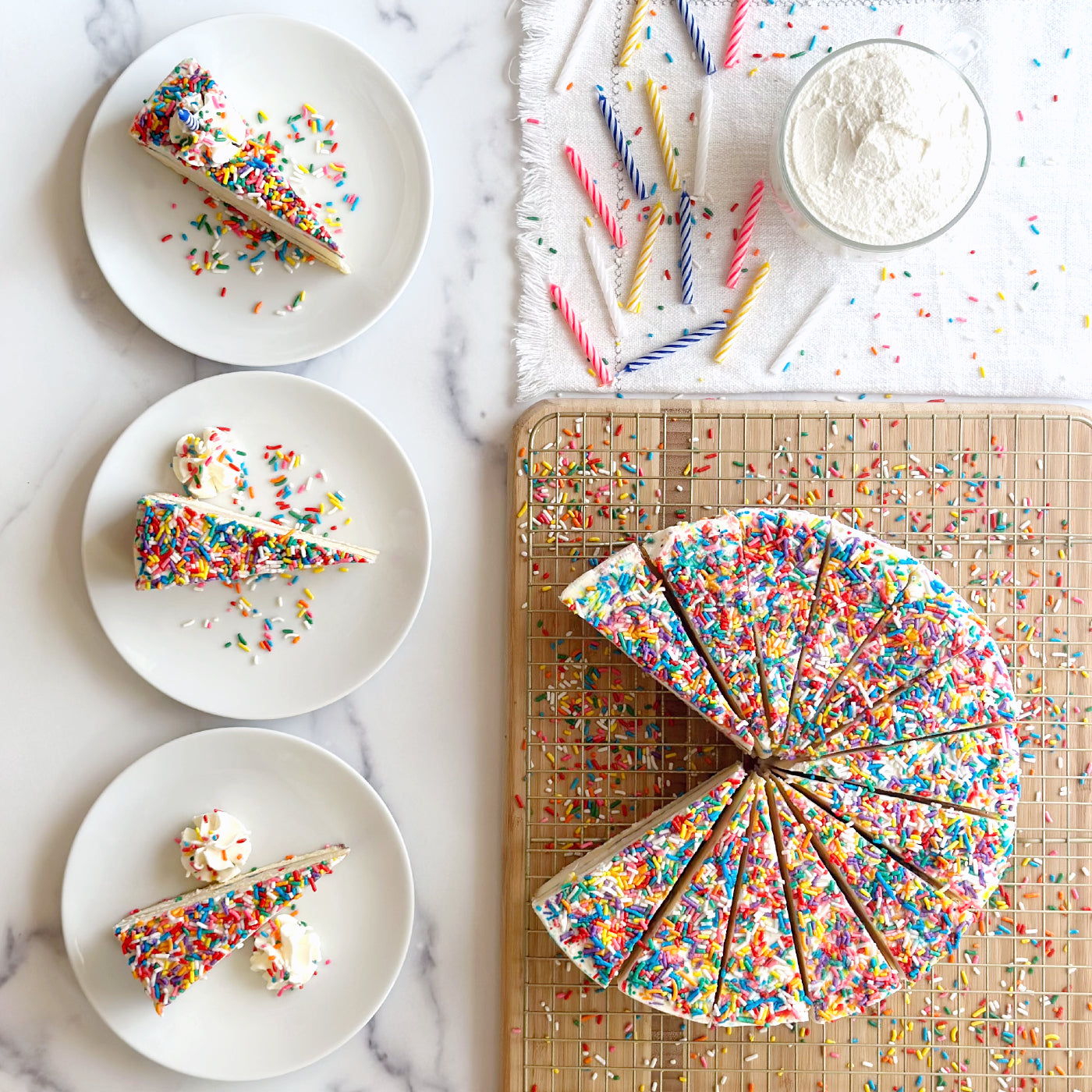 Beautiful 10 inch handcrafted birthday cake cheesecake topped with bright and colorful sprinkles, and three individual slices with more sprinkles and homemade whipped icing.