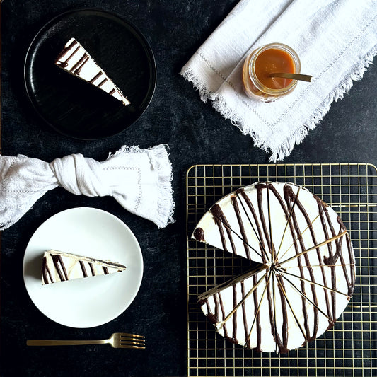 Indulgent 10 inch handcrafted marble brownie cheesecake topped with an elegant chocolate swirl, and two individually plated slices of rich marble brownie swirl cheesecake