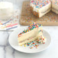 Velvety slice of birthday cake cheesecake with a thick layer of birthday cake baked-in, topped with our sweet cream cheese icing and then covered in colorful sprinkles with an added swirl of homemade whipped icing on the side