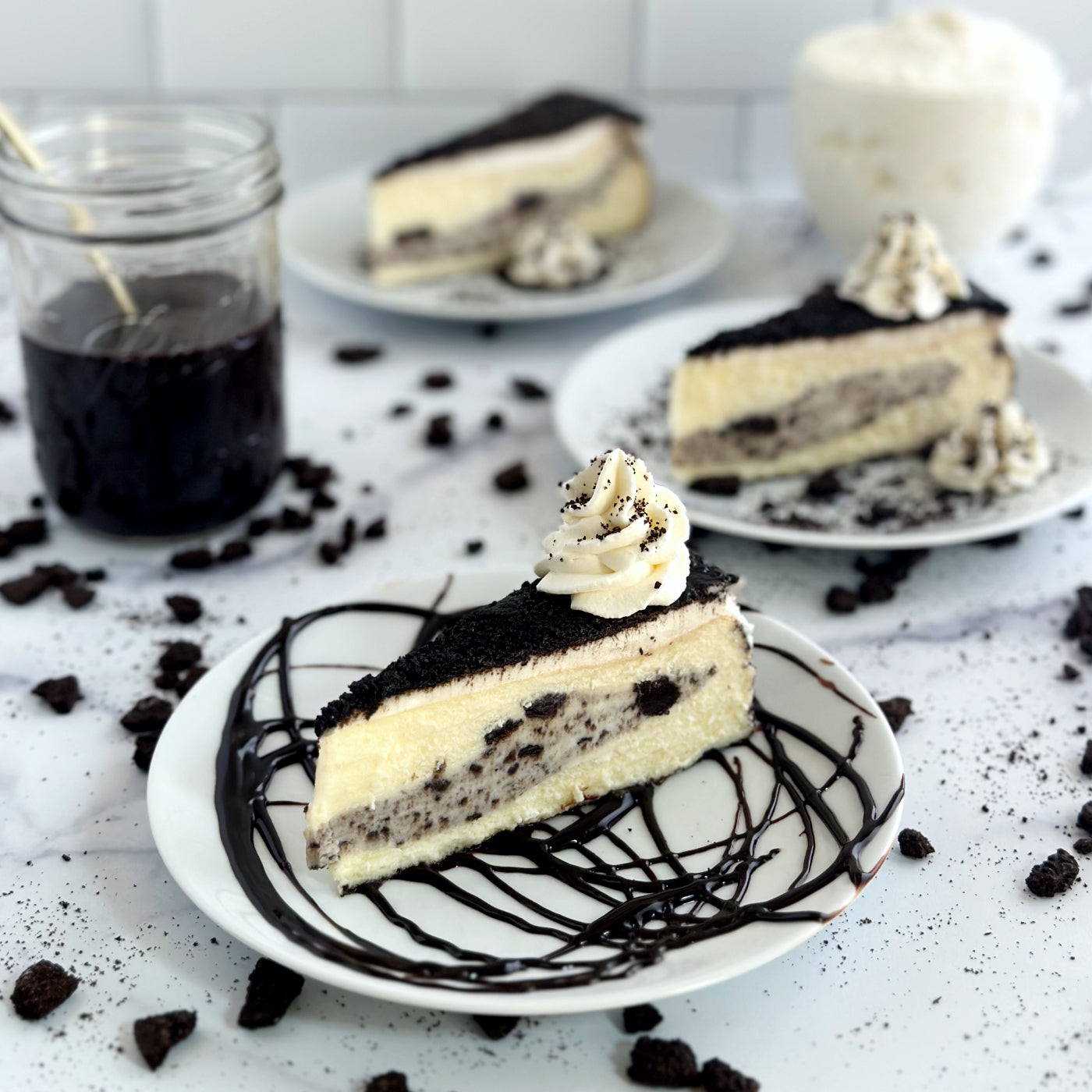 Velvety slice of Cookies & Cream Cheesecake with a thick layer of cookies and cream baked-in, sitting on a homemade chocolate swirl and topped with chocolate cookie crumbles and an elegant swirl of whipped cream.