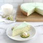Velvety slice of Key Lime cheesecake plated with lime garnishes and homemade whipped cream