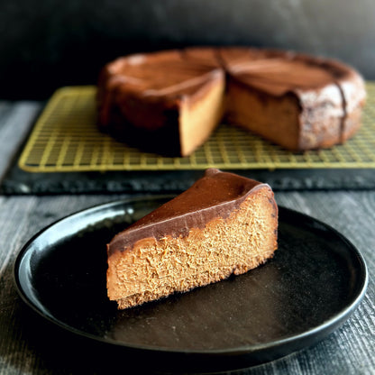 Velvety slice of chocolate cheesecake topped with a smooth layer of rich chocolate ganache