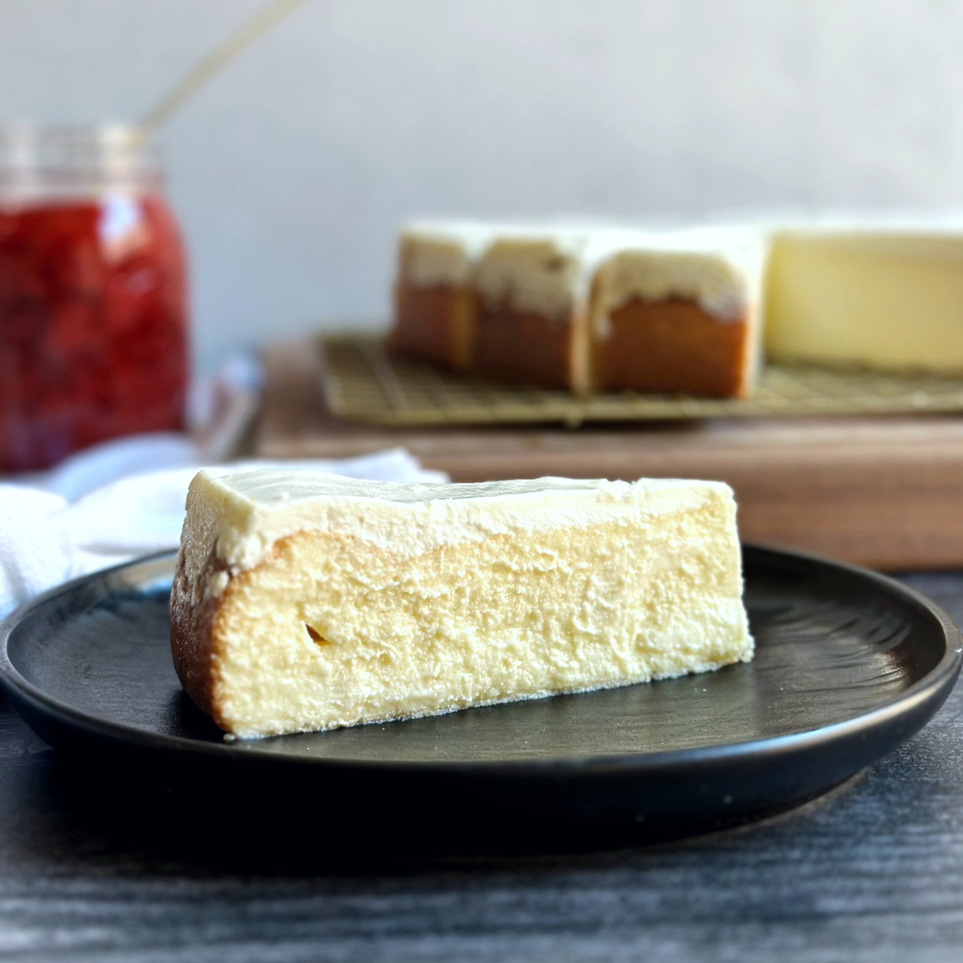 Velvety slice of Laura's Classic Cheesecake with a smooth layer of sweet cream cheese icing on top